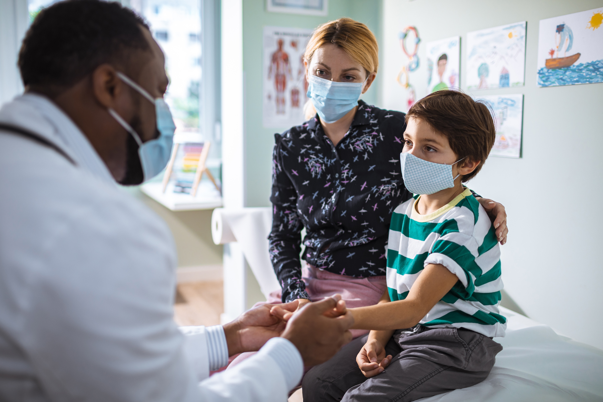 Close up of a pediatrician having a check up on his patient, all wearing masks.